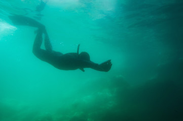 Silhouette of a free diver entering underwater cavern