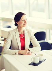 happy woman sitting at table in restaurant