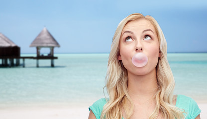 happy woman or teenage girl chewing gum on beach