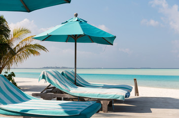 Obraz na płótnie Canvas parasol and sunbeds by sea on maldives beach