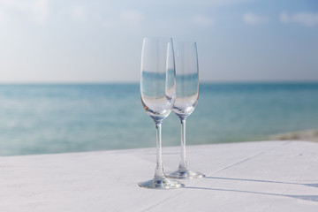  close up of two champagne glasses on beach 