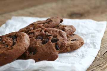 Cookies with chocolate chip on parchment paper napkin on wooden background