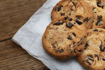 Cookies with chocolate chip on parchment paper napkin on wooden background