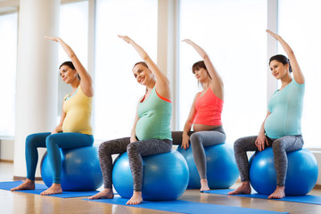 Naklejka premium happy pregnant women exercising on fitball in gym