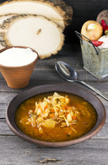Russian cabbage soup in clay plate on a dark wooden background