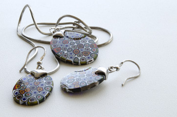 pendant and earrings made from Murano glass in a silver frame on a light background
