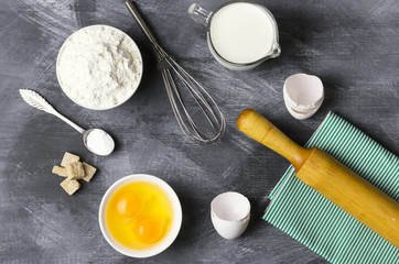 Fototapeta na wymiar Ingredients for pastries: flour, eggs, milk against a dark backg