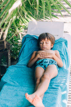 Boy sleeping on a sun lounger on beach