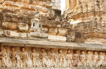 Sculptures, carved temple walls and body of Buddha at Sukhothai historical park, Thailand.