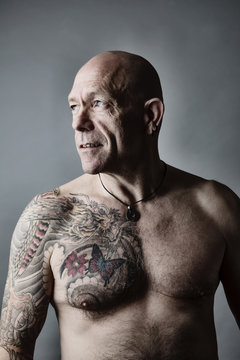 Portrait of bald man with tattoo on chest and arms