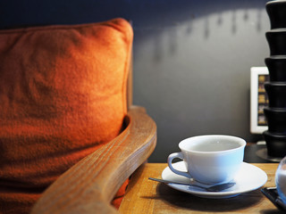 A cup of coffee put on table near armchair