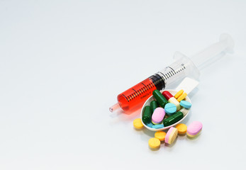 many tablets and pill on spoon and liquid drug in syringe