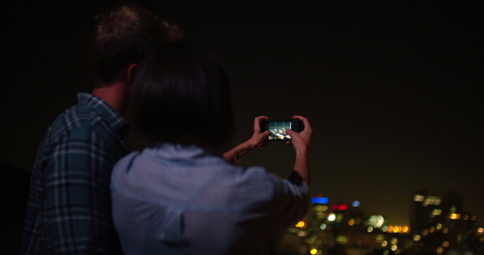 Happy couple taking picture of the city from the rooftop