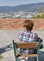 Fototapeta premium Woman sitting on park bench with Graz cityscape, Austria