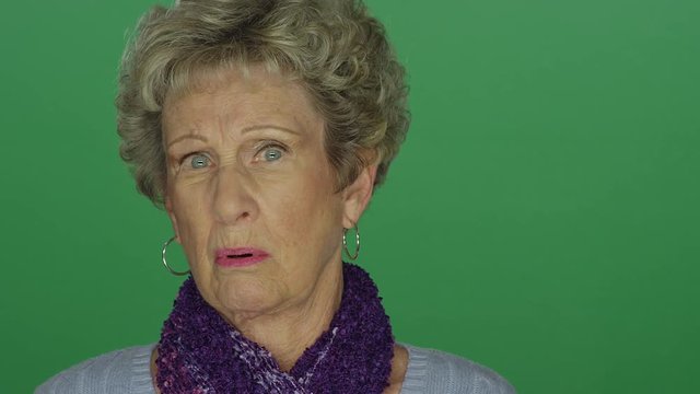 Older woman looking shocked and appalled, on a green screen studio background