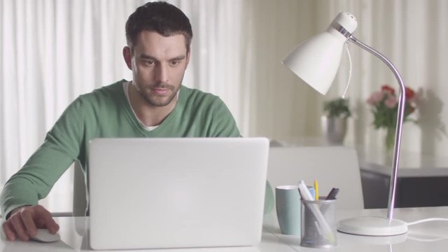 Man is working on a laptop computer at home. Shot on RED Cinema Camera.