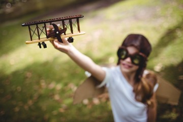 Girl playing with toy airplane outdoors