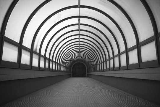 Semicircular long corridor. Illuminated way. Black and white.