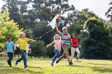 Cheerful children playing with kite in park