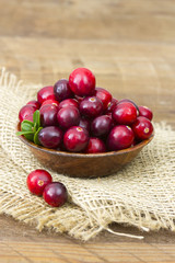 Cranberries in wooden bowl on wooden background