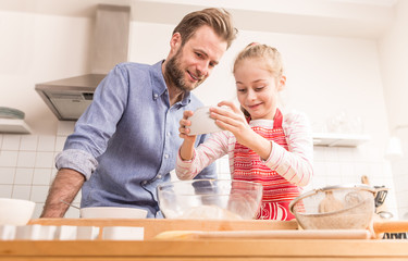 Father and daughter preparing cookie dough in the kitchen