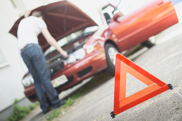 Warndreieck mit Autopanne im Hintergrund