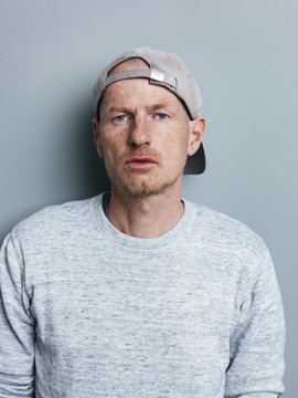Portrait of man with baseball cap in front of gray background