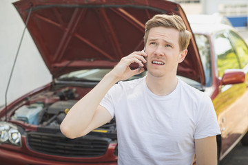 Junger Mann hat Autopanne und telefoniert
