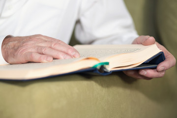 An old man hands holding the Koran. Selective focus