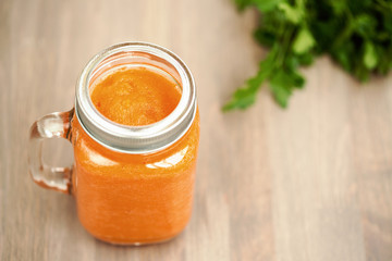 Healthy carrot smoothie in a jar on wooden background with parsley. Sepia toning. Shallow dof
