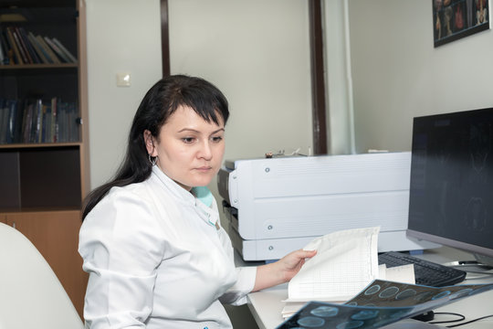 A brunette female doctor examining CT scanner results