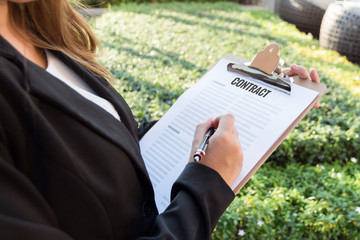 Businesswoman signing a contract in the garden