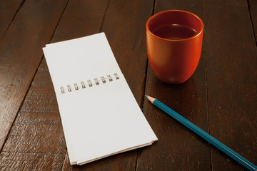 pencil,notebook,tea in cup on wood background.