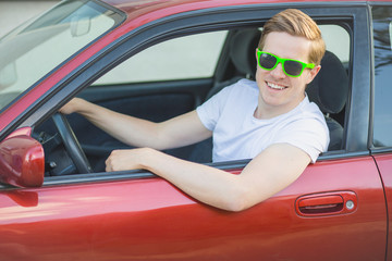 Junger Mann mit Sonnenbrille sitzt im Auto