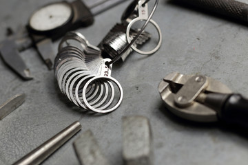 Obraz na płótnie Canvas Tools set of jewellery. Jewelry workplace on metal background. Finger sizing for rings, beam compass, pincer, nippers.