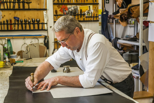 Saddler cutting piece of leather with stencil
