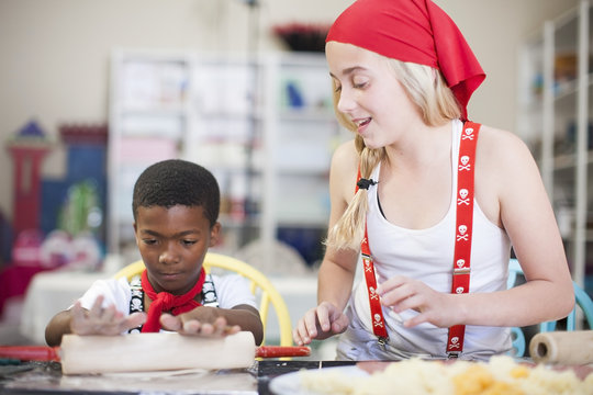 Children dressed up as pirates using rolling pin