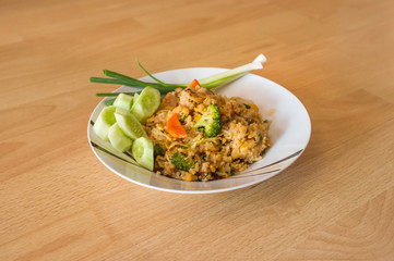 Thai food - fried rice on white dish with wood background, selective focus on front object