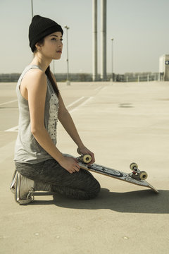 Young woman with skateboard on parking level