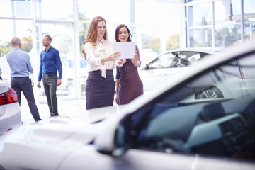 Two women at car dealer with digital tablet