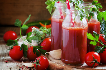 Smoothies of tomatoes and spices in glass bottles with festive r