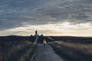 France, Brittany, Pointe du Raz, boy walking towards lighthouses Phare de la Vieille and Phare de Tevennec