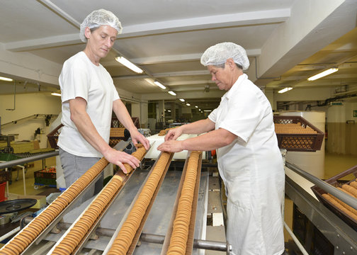 Germany, Saxony-Anhalt, two women controlling cookies on production line in a baking factory