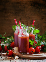 Smoothies of tomatoes and spices in glass bottles with festive r