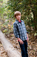 Young handsome boy standing on a log outdoors.