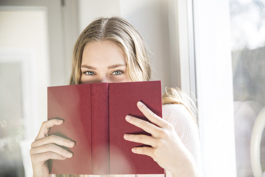 Woman Hiding Behind Red Book