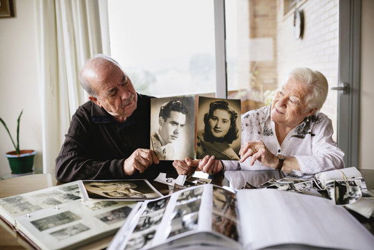 Senior couple showing old pictures of themselves