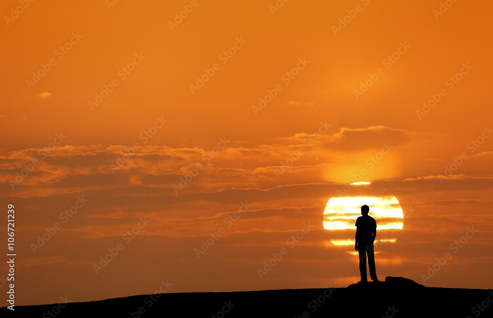 Wall mural sunset landscape with silhouette of a standing man on the background of solar disk and colorful yell