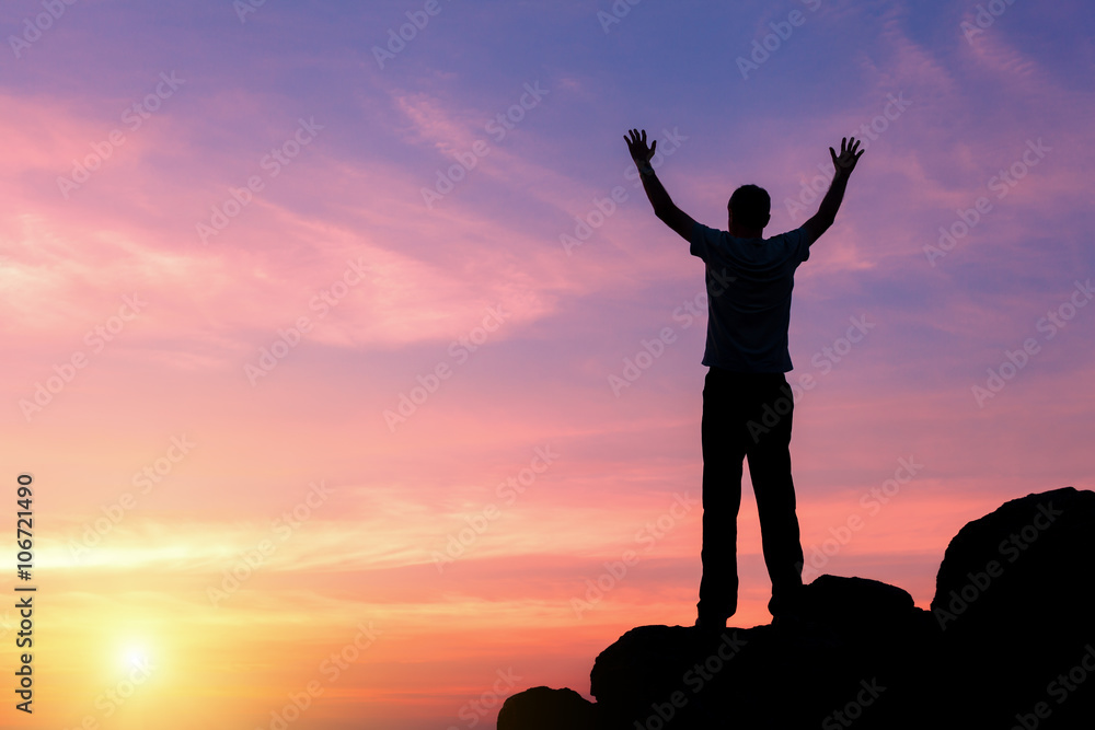 Wall mural landscape with silhouette of a standing happy man with raised-up arms on the background of colorful 