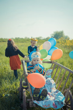 Three children on the move with wooden trolley and balloons